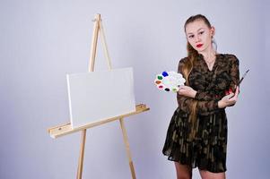 mooie vrouw kunstenaar schilder met borstels en olie canvas poseren in studio geïsoleerd op wit. foto