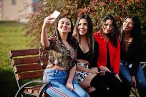 groep van vier gelukkige en mooie latino-meisjes uit ecuador poseerden op straat en maakten selfie op de telefoon. foto