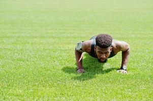 Afro-Amerikaanse mannelijke atleet in sportkleding doet push-up oefening in het stadion. foto