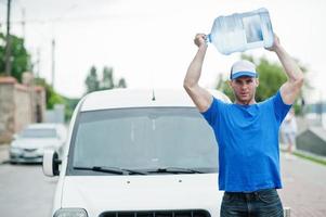 bezorger vooraan bestelwagen die flessen water levert. foto