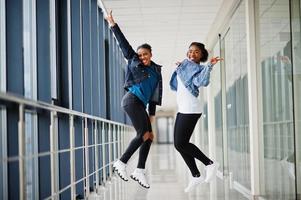 twee Afrikaanse vriendinnen in jeans jasje springt samen binnen. foto