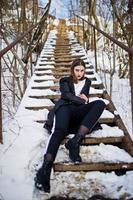 modieuze lange benen brunette model in lange zwarte mantel poseerde buiten op winterdag. foto