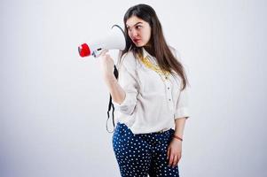 portret van een jonge vrouw in blauwe broek en witte blouse poseren met megafoon in de studio. foto