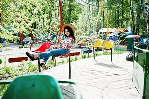 portret van brunette meisje in roze bril en hoed met ijs in pretpark. foto