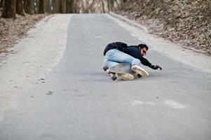 niet vallen van een skateboard. straatstijl Arabische man in bril met longboard longboarden op de weg. foto