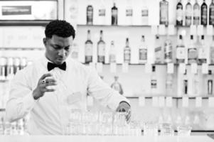 Afro-Amerikaanse barman draagt een vlinderdasreinigingsbril aan de bar. foto