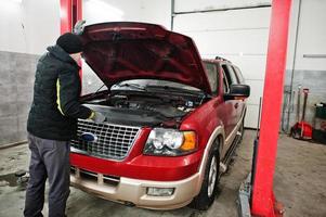 automonteur stelt Amerikaanse SUV-auto in voor diagnostiek en configuratie in werkplaatstankstation.. foto