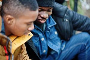 twee Afrikaanse mannelijke vrienden zitten en kijken samen op de telefoon. foto