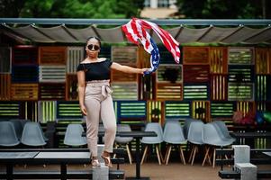 stijlvolle Afro-Amerikaanse vrouw in zonnebril poseerde buiten met usa vlag. foto