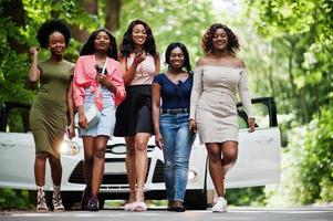 groep van vijf gelukkige Afro-Amerikaanse wandelen tegen witte auto. foto