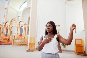 Afro-Amerikaanse vrouw bidden in de kerk. gelovigen mediteren in de kathedraal en geestelijke gebedstijd. afro meisje houdt handen omhoog. foto