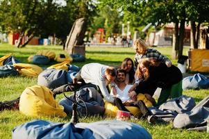 jonge multi-etnische groep mensen kijken naar film op poef in openluchtbioscoop. foto