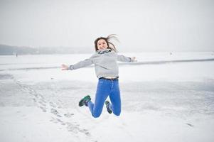 grappig springend meisje op bevroren meer in de winterdag. foto