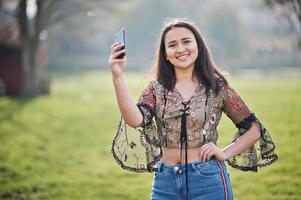 mooie latino model meisje uit ecuador slijtage op jeans gesteld op straat met mobiele telefoon. foto