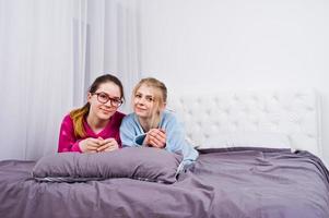 twee vrienden meisjes in pyjama plezier op bed op kamer. foto