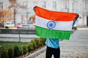 Zuid-Aziatische Indiase mannelijke student met de vlag van india buiten geposeerd. foto