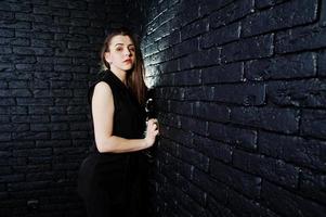 portret van een mooie brunette meisje in zwarte jumpsuit in de studio naast de bakstenen muur. foto