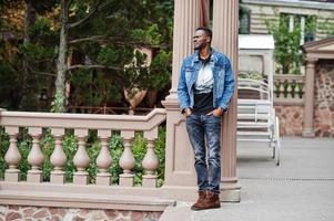 jonge aantrekkelijke serieuze Afro-Amerikaanse man model. moderne knappe kerel in jeans jasje die zich op stedelijke stadsstraat bevindt. foto