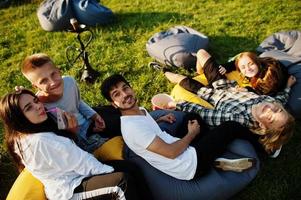 jonge multi-etnische groep mensen kijken naar film op poef in openluchtbioscoop. foto