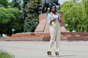 stijlvolle Afro-Amerikaanse zakenvrouw op broek met jarretel en blouse poseerde buiten. foto