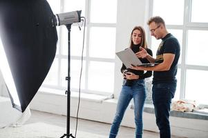 fotograaf legt over het schot uit aan zijn assistent in de studio en kijkt op laptop. teamwork en brainstorm. foto