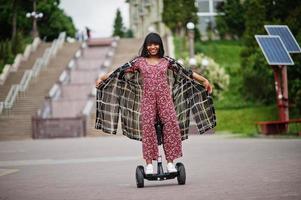 mooie afrikaanse amerikaanse vrouw die segway of hoverboard gebruikt. zwarte meid op zelfbalancerende elektrische scooter met twee wielen. foto