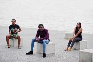 drie Afro-Amerikaanse vrienden zittend op stenen kubussen buiten. foto