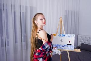 mooie vrouw kunstenaar schilder met borstels en olie canvas poseren bed op kamer. foto