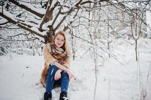 portret van blond meisje in glazen, rode bontjas en sjaal op winterdag. foto