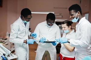 multiraciale tandarts artsen team. drie Afro-Amerikaanse mannelijke artsen met een blanke vrouwelijke arts. ze discussiëren en lachen. foto