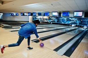 vervagen foto van terug Zuid-Aziatische man gooit bowlingbal op beweging op steegje.