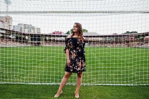 portret van een fantastisch meisje in jurk en hoge hakken naast de voetbalpoorten in het stadion. foto