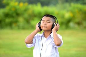 schoolkinderen luisteren graag naar muziek met een koptelefoon op het gazon, redido-koptelefoons. foto