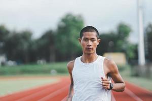 atleet sportman runner training uitgevoerd op baan in het stadion in de ochtend. runner man met wit vest om te oefenen met hardlopen, bereid je voor op wedstrijdrace. sportconcept. foto