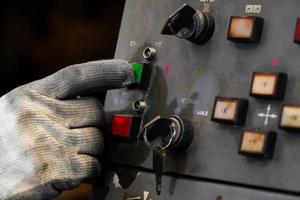 vuile handschoenen druk op de groene startknop op het bedieningspaneel van de cnc-machine. foto