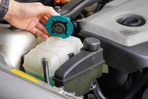 monteur inspecteert het expansievat met groene antivries. koelvloeistofpeil in het radiateursysteem van de auto. auto-onderdelen foto