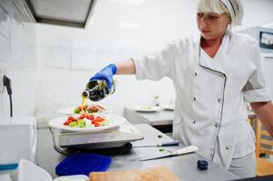 vrouwelijke chef-kok die salade in Italiaanse restaurantkeuken voorbereidt. foto