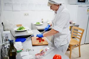 vrouwelijke chef-kok die salade in Italiaanse restaurantkeuken voorbereidt. foto