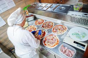 vrouwelijke chef-kok die pizza in restaurantkeuken voorbereidt. foto