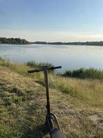 elektrische scooter in een park in de buurt van het meer. het concept van ecologie en elektrisch vervoer foto