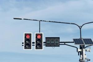 stoplicht rode kleur bidirectioneel met numeriek lichtbord. hangend aan een stalen arm die uit de pilaar steekt. installeer verlichtingslampen met zonnepanelen. onder de blauwe lucht en witte wolken op dagen. foto