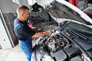 auto reparatie en onderhoud thema. monteur in uniform werken in autoservice, motor controleren. foto