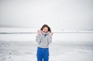 grappige meisjesslijtage op hoody sweater en jeans, bij bevroren meer in de winterdag. foto