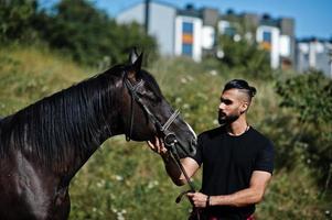 Arabische lange baard man slijtage in het zwart met Arabisch paard. foto