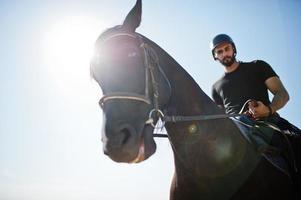 arabische lange baard man draagt zwarte helm, berijdt arabisch paard. foto