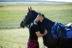 Arabische lange baard man slijtage in het zwart met Arabisch paard. foto