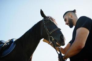 Arabische lange baard man slijtage in het zwart met Arabisch paard. foto