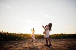 twee mooie jonge zwarte vrienden vrouw dragen zomerjurk poseren in een zonnebloemveld. foto