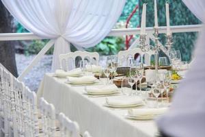 lege feestzaal klaar om gasten te ontvangen op het zomerterras. witte feesttafel foto