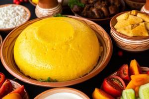 zelfgemaakte Roemeense gerechten met polenta, vlees, kaas en groenten. heerlijke maïspap in kleischotels. mamaliga of polenta, een traditioneel gerecht in de Moldavische, Hongaarse en Oekraïense keuken. foto